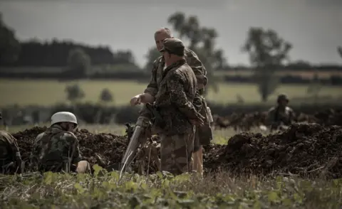 The Victory Show official photography team  Actors dressed in camouflage clothing in a field 