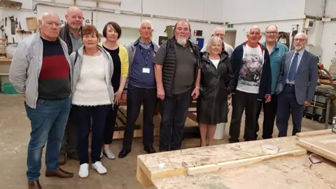 Broadstairs Town Shed A group of 11 people of mixed gender and ages pose in the workshop of the Broadstairs Town Shed.