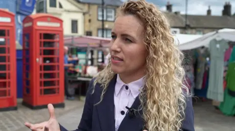 Katie White, MP for Leeds North West, with long blonde curly hair.