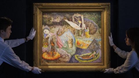 Two members of staff at Sotheby's auction house in New York display Leonora Carrington's Les Distractions de Dagobert