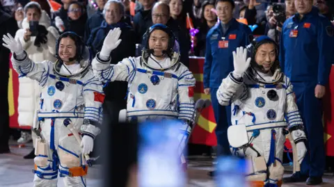 Astronautas da EFE (da esquerda para a direita) Wang Haoze, Song Lingdong e Cai Xuzhe caminham até o carro que os levará ao local da missão espacial tripulada Shenzhou-19, perto de Jiuquan, na província de Gansu