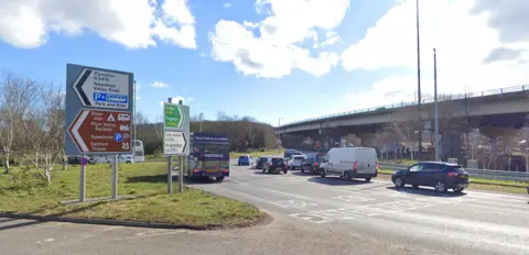 Google A roundabout under a flyover, with signs to Exeter, Paignton and Plympton as well as Plymouth City Centre.