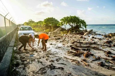 getty People clean up a flooded beach