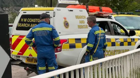 Two coastguard workers by a truck 