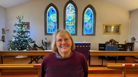 Reverend Pam Davies stands in front of the altar at Huggens College in Northfleet