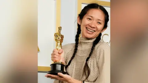 A woman with black hair holding an award.