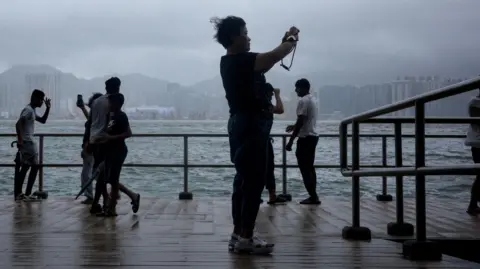 Getty Images People watch waves along the seaside as typhoon Ragasa moves away on September 24, 2025 in Hong Kong, China. 