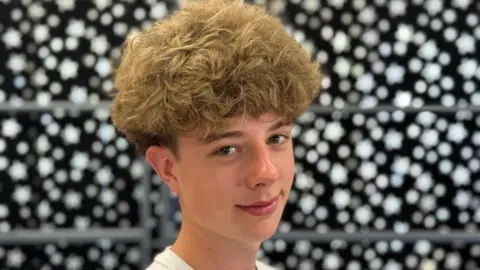 BBC Mathieu is smiling into the camera, he is 15 and has brown curly hair.