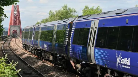 Getty Images A ScotRail trains heads along the tracks towards the Forth Rail Bridge on a sunny day.