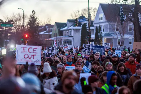 Getty Images People demonstrate against ICE during a vigil honouring a woman who was shot and killed by an immigration officer earlier in the day in Minneapolis, Minnesota, on 7 January. Protesters carry signs that say "ICE OUT".
