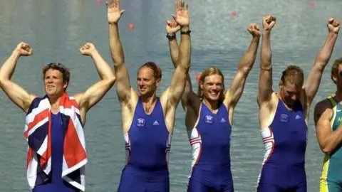 PA Media Great Britain rowers (left to right) James Cracknell, Steve Redgrave, Tim Foster, and Matthew Pinsent celebrate after winning the Gold Medal in the men's coxless four final at the Olympic Games in Sydney in September 2000. All have their arms held aloft 