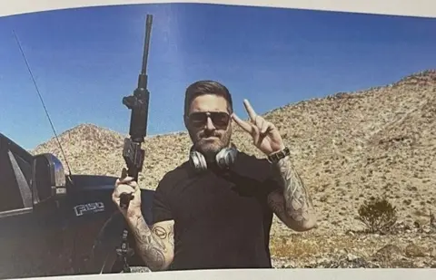 A photo of the matchday program with the headline "Chairman's Notes" and below that a photo of Peter McCormack holding a large black gun in his right hand and doing the V-peace sign with the other. He is standing with a scrubland behind and a black vehicle to his right.