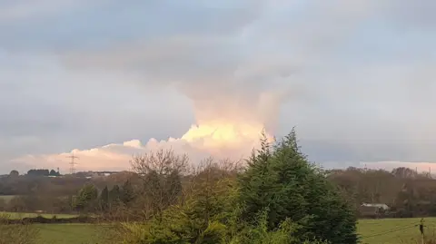 Heidi-Eye/BBC Weather Watchers A towering mass of cloud rises behind the distant landscape, looking very much like a threatening thunderstorm.