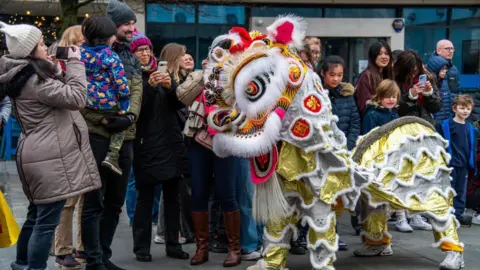 Visit Southampton A golden lion stands in front of spectators in a city street.