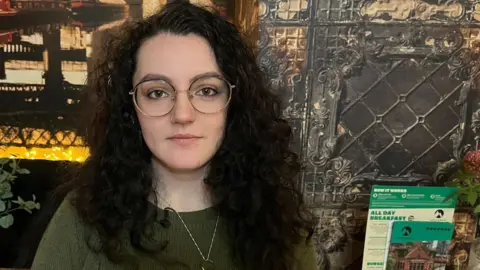 Eleanor Maher is sitting in a restaurant during a Let's Talk About Loss meet-up. She is staring directly at the camera.