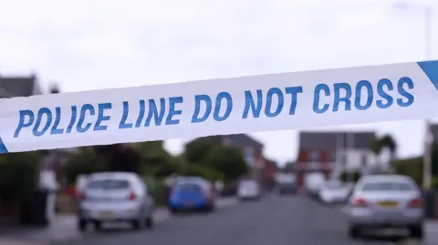 A stock image of white and blue police tape with the wording "police line do not cross".