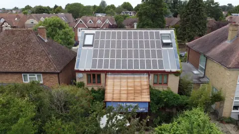 A view from above of the fitted solar roof at the back of the house surrounded by more traditional tiled roofs in the neighbourhood