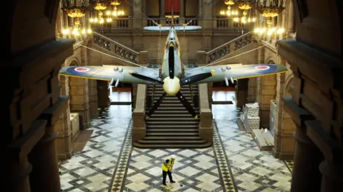 Cleaner underneath spitfire in Kelvingrove