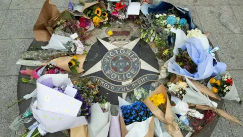 Getty Images Floral tributes encircle a Victoria Police emblem