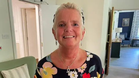 Wendy Critchlow smiles at the camera in a floral top