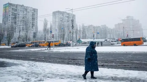 Reuters A woman walks through snow in a Ukrainian city.