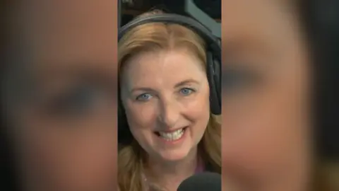 Julie Wilson Nimmo has blonde hair and is wearing headphones.