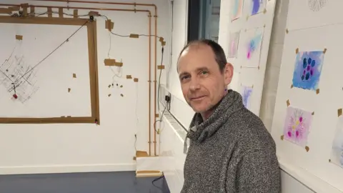 The Residence Artist, Stuart Moore. standing by his work