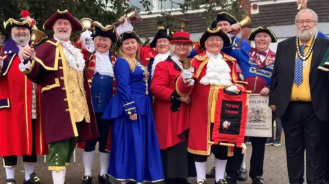 Ten town criers posing for their photographs, smiling