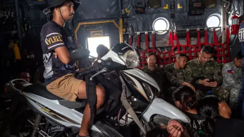 A man sits on a motorbike during a flight to Pagasa