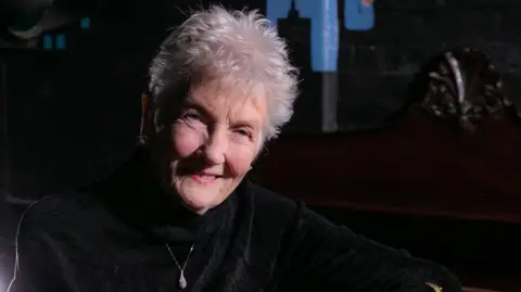 A smiling Peggy Seeger posing for the cover of her new album Teleology.
