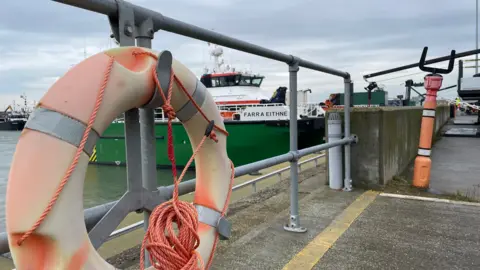 Ben Schofield/BBC A life ring on the quayside at the Port of Lowestoft with a service vessel in the background