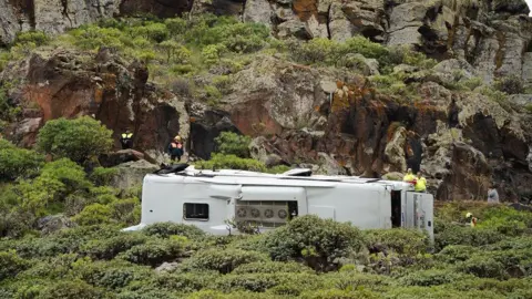 Europa Press Canarias via Getty Images A close up of the bus on its side and rescue workers next to it