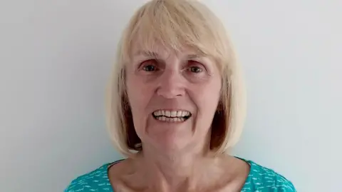 Karen Norton Karen Norton, who has shoulder length straight blonde hair and is wearing a turquoise top.