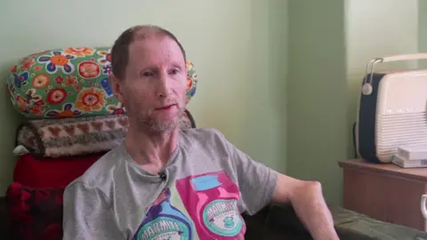 Peter Jeapes sitting on chair in his living room