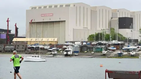 BBC A man running with BAE Systems in the background