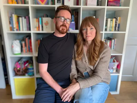 Stephen and Cheryl Webb pictured at home in front of an Ikea Kallax bookcase