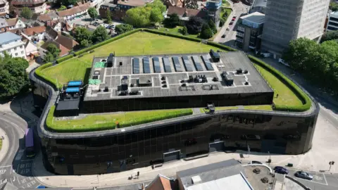 An aerial view of the Willis building in Ipswich. The sides of the building are glass panels with a garden on its roof.