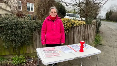A woman standing behind a camping table with political leaflets on it