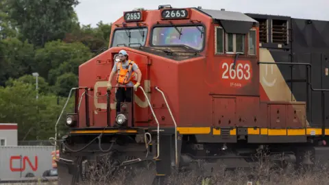 A worker rides on the front of a train at the CN Rail freight depot in Hamilton, Ontario, Canada August 19, 2024.