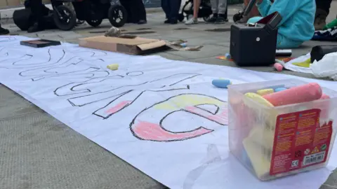 George Carden/BBC A banner with the word STRIKE written on it with coloured chalk, which sits in a plastic box next to it