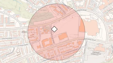 Plymouth City Council A map showing a residential area with streets, housing blocks, schools, and green spaces clearly marked. At the centre is a white diamond symbol. Around that point is a large shaded circular area, coloured in light red and orange tones, indicating a defined radius or zone of interest.