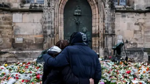 Two people mourn site in front of a church in Magdeburg