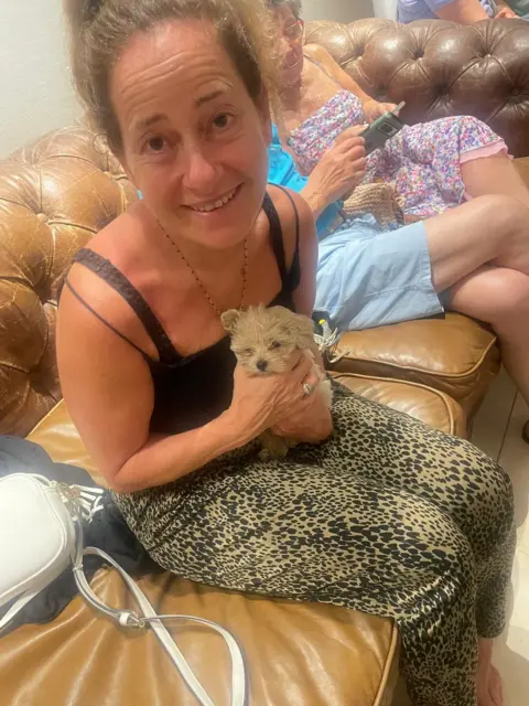 Deborah Claydon pictured in her hotel's shelter in Israel holding a puppy