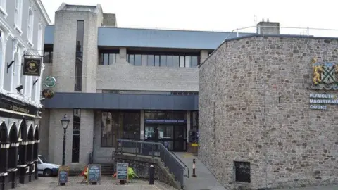 Exterior of Plymouth Magistrates' Court. It is a large brick building. A pub is next door to it on the left-hand side.