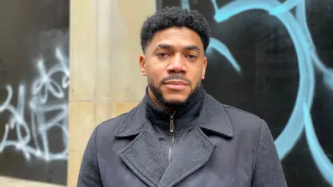 BBC Dimitri Moses standing in Hockley in Nottingham city centre with the wall of a building behind him