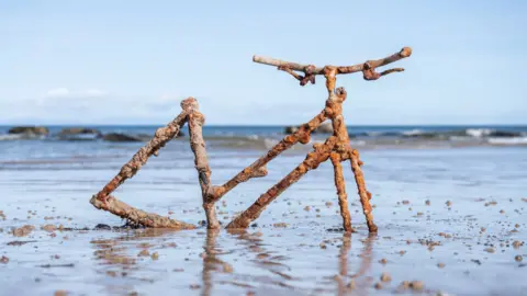 A rusty bike frame embedded in a beach at Lossiemouth