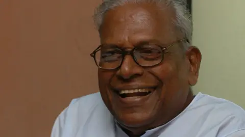 Getty Images vs Achuthanandan visto sorrindo em uma foto em close, vestindo uma kurta branca