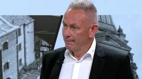 Marcus farmer, wearing a white shirt and a black jacket