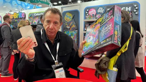 BBC Jay Foreman of Basic Fun holds an iPhone and a Lite-Brite colour toy 