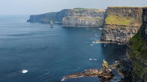 The Cliffs of Moher beside a deep blue see and a grey sky